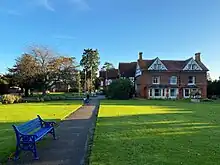 A photo of the former hunting lodge at Garth Park in the sunshine with a green lawn in the foreground.