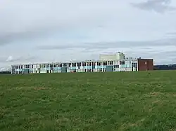 A photo of a long building taken from a field nearby