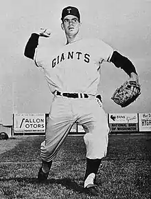 A man in a light baseball uniform with dark undersleeves and cap