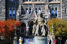 Upper portion of the statue with the steps and stone façade of Healy Hall in the background