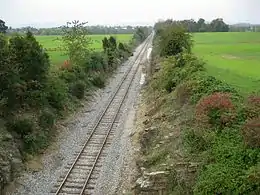 Photo shows a railroad cut from underneath an overpass. In the distance the Catoctin Mountains can barely be seen.