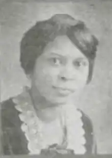 A young Black woman wearing a dark top with a white lace collar