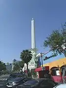 Side view of the  Alex Theatre and the 100-foot-tall (30 m) art-deco column with neon lights, topped by a spiked, neon sphere that gave it a "starburst" appearance (2014).