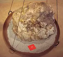 Relative sizes of an 860-kilogram (1,900 lb) rock ore, and the 30 grams (1.1 oz) of gold that can be extracted from it