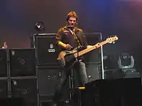 A bassist is onstage with a number of large speaker cabinets.