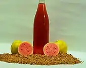 A bottle of guava seed oil surrounded by fruit