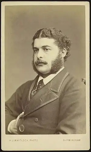 Head and shoulders of Sullivan as a young man, wearing a moustache, long sideburns and a serious expression