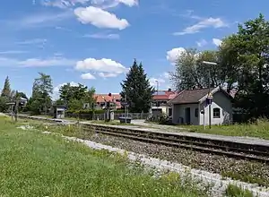 Overgrown railway line with side platform and single-story shelter