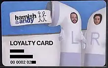 The front of a Hamish & Andy loyalty card with cardholder name and number redacted. Atop a blue background is both Hamish and Andy in earphone costumes. On the left, black text reads 'LOYALTY CARD' and the cardholder's name and card number follows. The Hamish & Andy logo sits in the top left corner.