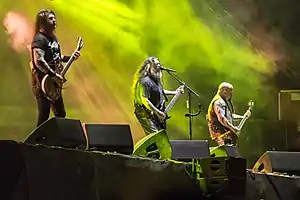 Three band members of Slayer performing.