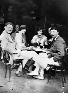 photograph of three men and two women sitting at a sidewalk table