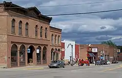 Row of one and two-story brick buildings interrupted by one mid-century wooden building