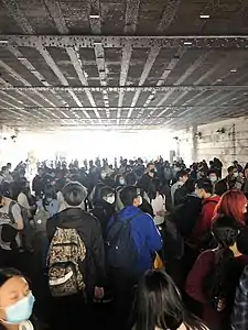 Hundreds of students crowding under a bridge due to a bomb threat.