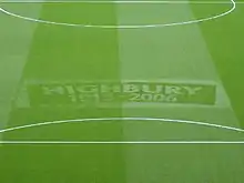 A photograph of a green football turf, with the words Highbury, 1913–2006 etched in the middle.