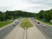 A photo down the centre of a freeway, taken from a bridge. The opposing lanes of the freeway are separated by grass.