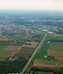 Aerial image of the beginning of a freeway, as it widens from two lanes to four lanes with a grass median. The image shows the rural-urban fringe of Waterloo