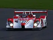 A view of a red and white sports car on a racing track