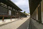 Long wooden building with white walls.