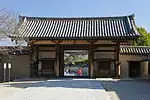 Wooden gate with white walls, red beams and a gabled roof.