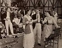 Film still, a courtroom scene, two women and one man in foreground.