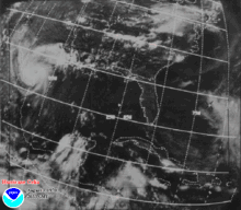 A black and white satellite image of a hurricane making landfall. The hurricane has a small faint eye and is located at the top left of the picture.