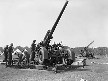 In an open area a large artillery gun points up to the sky