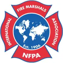 A red cross-shaped badge reading the name of the association, with a circular blue center depicting a white globe, with text underneath reading "established 1906"