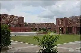 Grassy quadrangle in front of low, red buildings