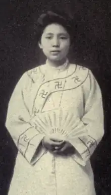 A young Chinese woman wearing a light-colored robe and holding a fan