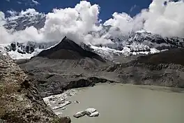 A view of the eastern extent of Imja Tsho. The image shows the Imja Glacier calving into the lake, as well as the surrounding peaks bathed in clouds.