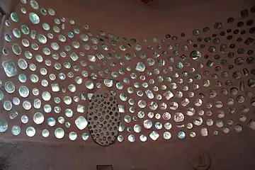 An interior bathroom wall that incorporates repurposed clear glass bottles into a bottle wall