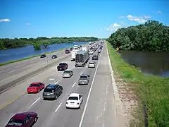 Floodwater is on both sides of a busy highway.