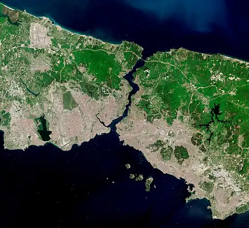 Satellite image showing a thin piece of land, densely populated on the south, bisected by a waterway