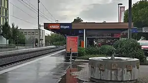 Single-story building with flat roof next to double track