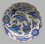 Iznik dish with an all-over design of composite lotus blossoms and rosettes overlapped in curved serrated leaves, c. 1545-1550. British Museum