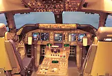 Cockpit of modern jet airliner, showcasing digital displays and instruments. Light enters through the windshield.