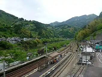 A view of the station platforms in 2015. A wheelchair user can be seen crossing the tracks at the level crossing.