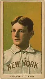 A man with light brown hair, wearing a white collared uniform with buttons down the front and the words "New York" on his chest looks to his right