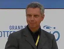 A man in a suit with a yellow lanyard.