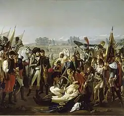 Oil painting featuring Napoleon in the foreground being presented by a soldier the body of Desaix. Desaix is wearing a white shirt and his chest is exposed to show the wound. Numerous and curious bystanders surround the scene.