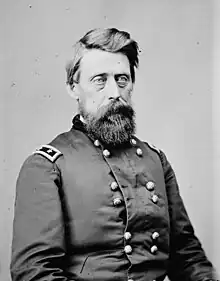 Black and white photo shows a bearded man with light-colored eyes. He wears a dark military uniform with two rows of buttons and the shoulder tabs of a major general (two stars).