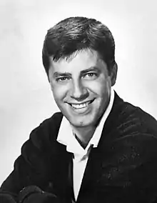 Black-and-white portrait photograph of a smiling man with short hair