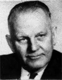 Black and white portrait photo of Roxburgh in a suit and tie