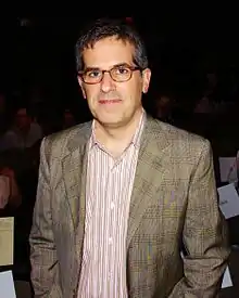 A photograph of a middle-aged man in glasses and a jacket