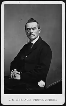 Formal photo of Barthe, fair-skinned and dark-haired, wearing mid-19th century business suit and pince-nez