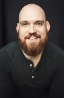 Smiling bald man with beard wearing a black shirt