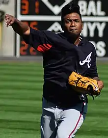 A baseball player in a navy jersey and gray pants