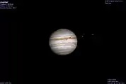 A computer-generated image showing a double shadow transit on Jupiter. The two satellites visible, Io and Europa, just to the right of the planet, are responsible for the shadows.