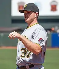 A man in a gray baseball uniform and black cap