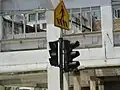 A typical pedestrian crossing traffic light in Kuala Lumpur with a countdown display and a pedestrian crossing sign above it.